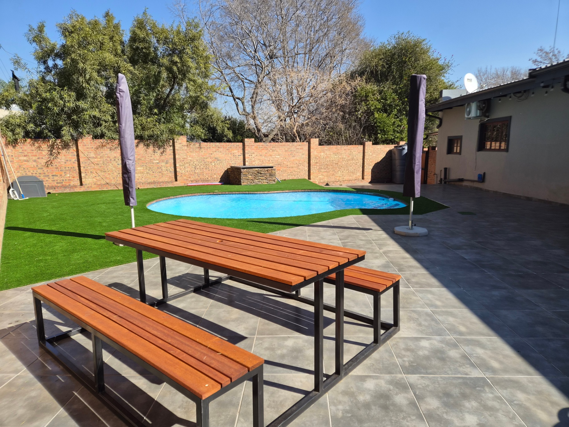 Poolside patio with wooden bench seating and umbrellas