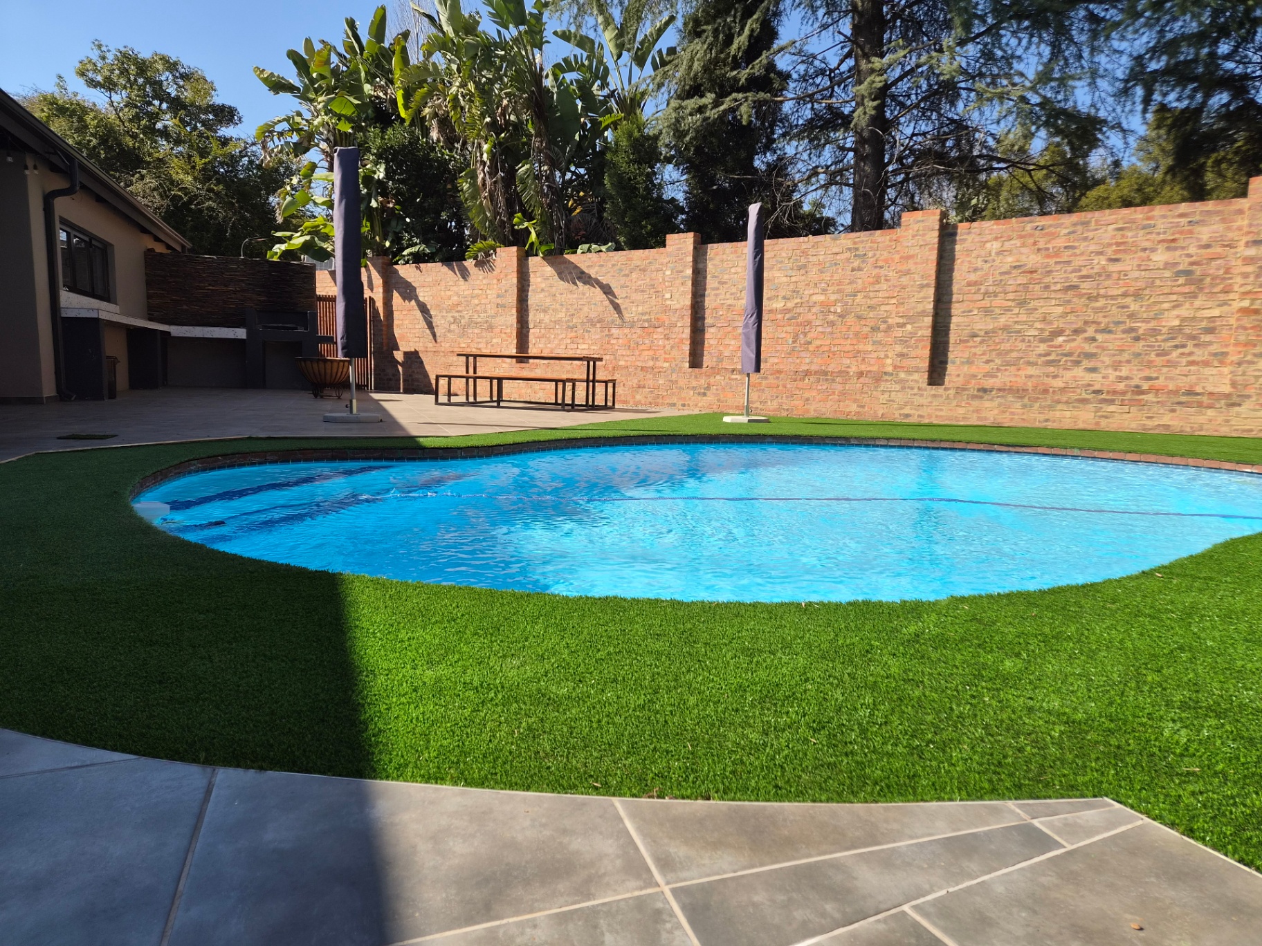 Swimming pool with artificial lawn and brick boundary wall